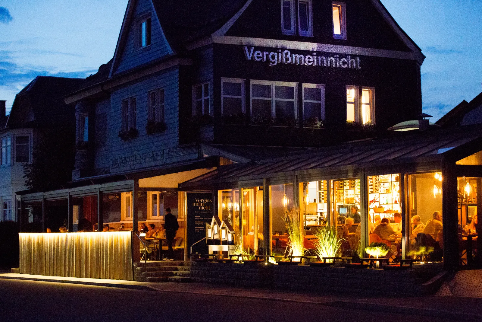 Das Restaurant & Hotel Vergissmeinnicht in Oberhof zur blauen Stunde mit warm erleuchteten Fenstern und beleuchtetem Wintergarten