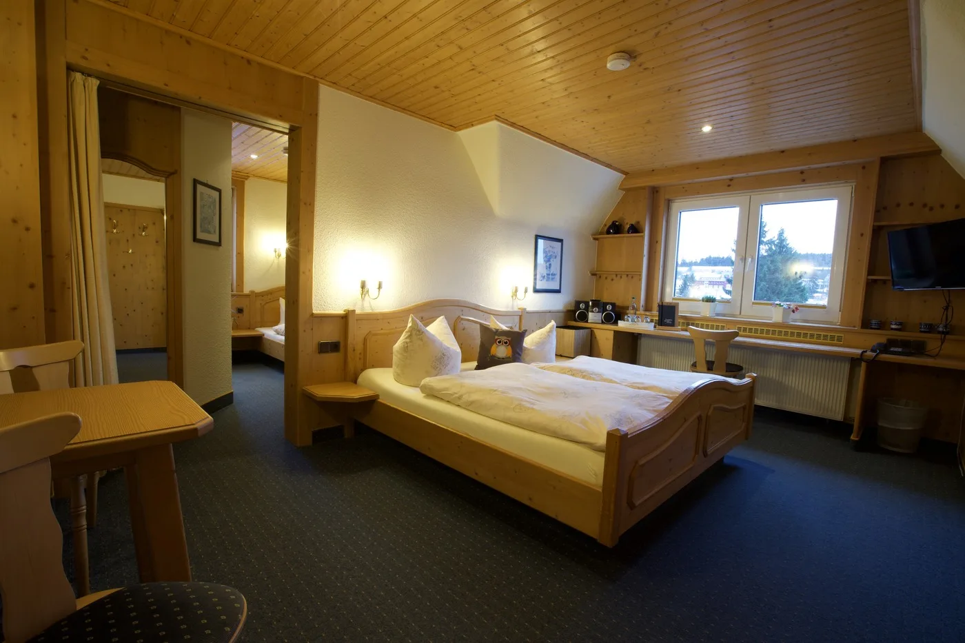 Dreibettzimmer mit mehreren Betten, Kiefernholzmöbeln und Dachschräge