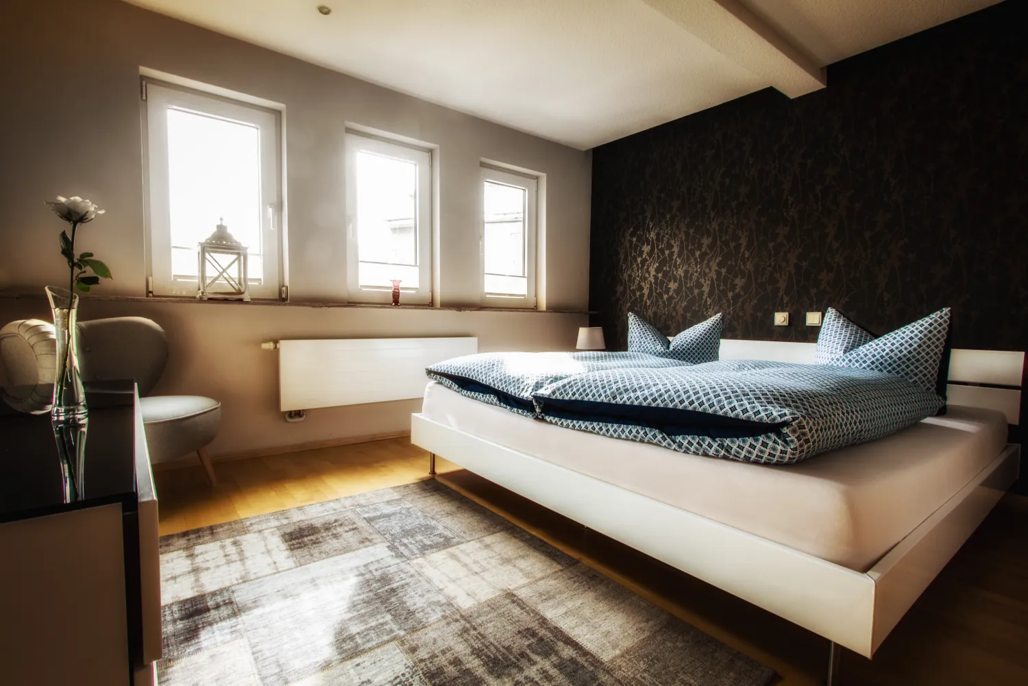 Helles Schlafzimmer im Ferienhaus mit Doppelbett, Akzentwand und großen Fenstern