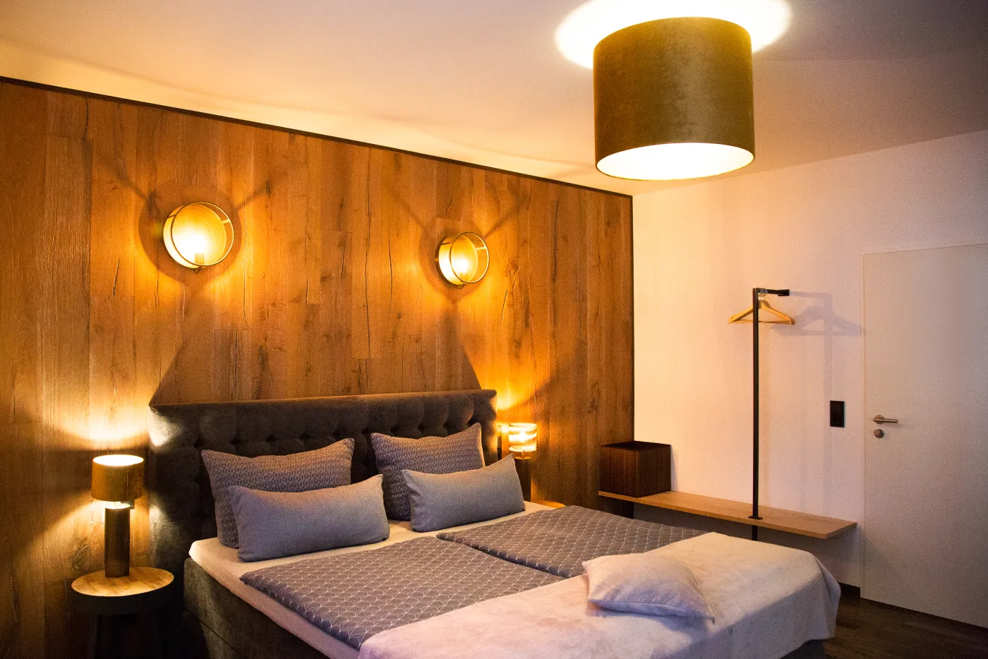 Komfortzimmer mit Eichenholz-Wand, Stehleuchte und warmer Beleuchtung