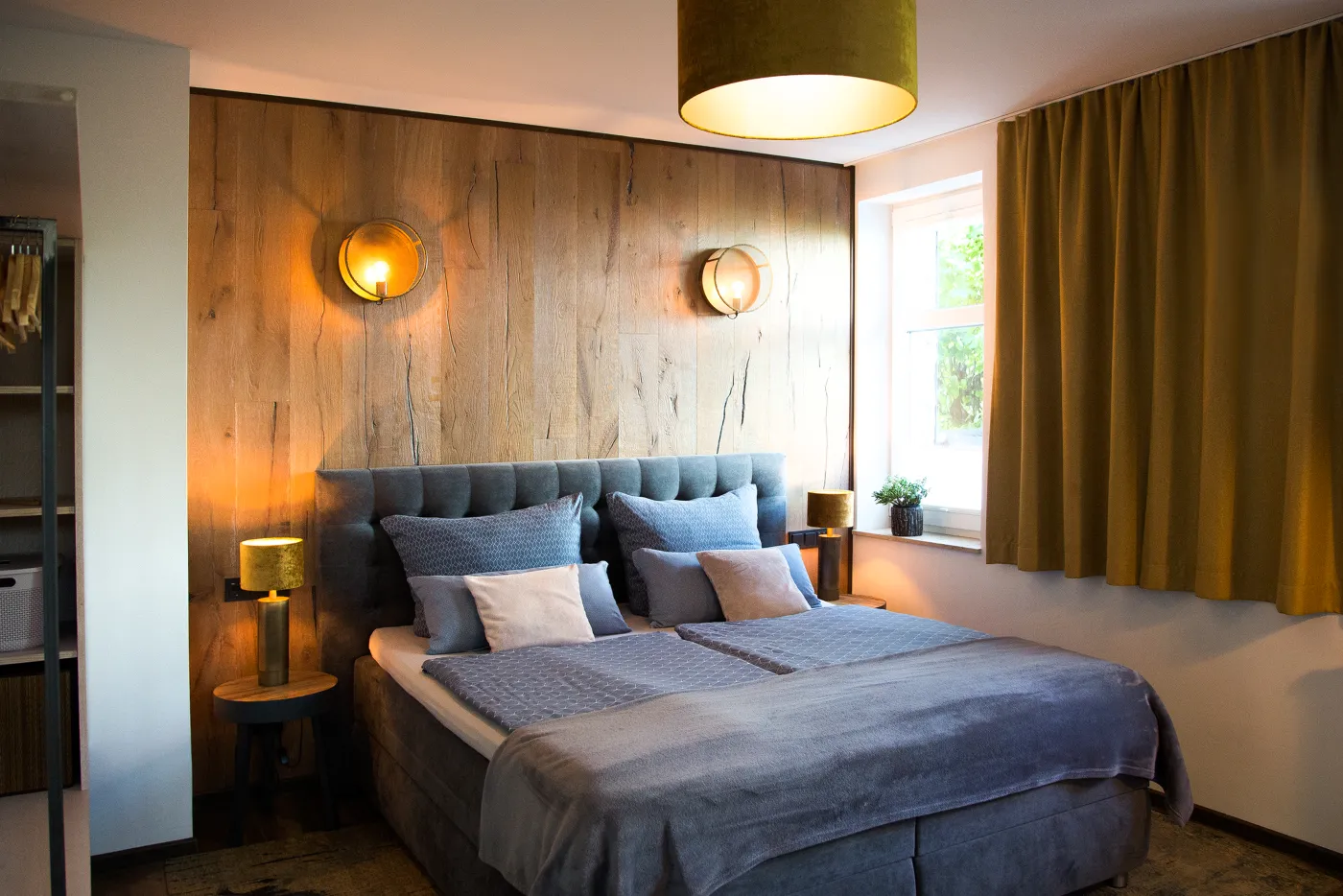 Komfortzimmer mit Fenster, Vorhängen und Holzwand